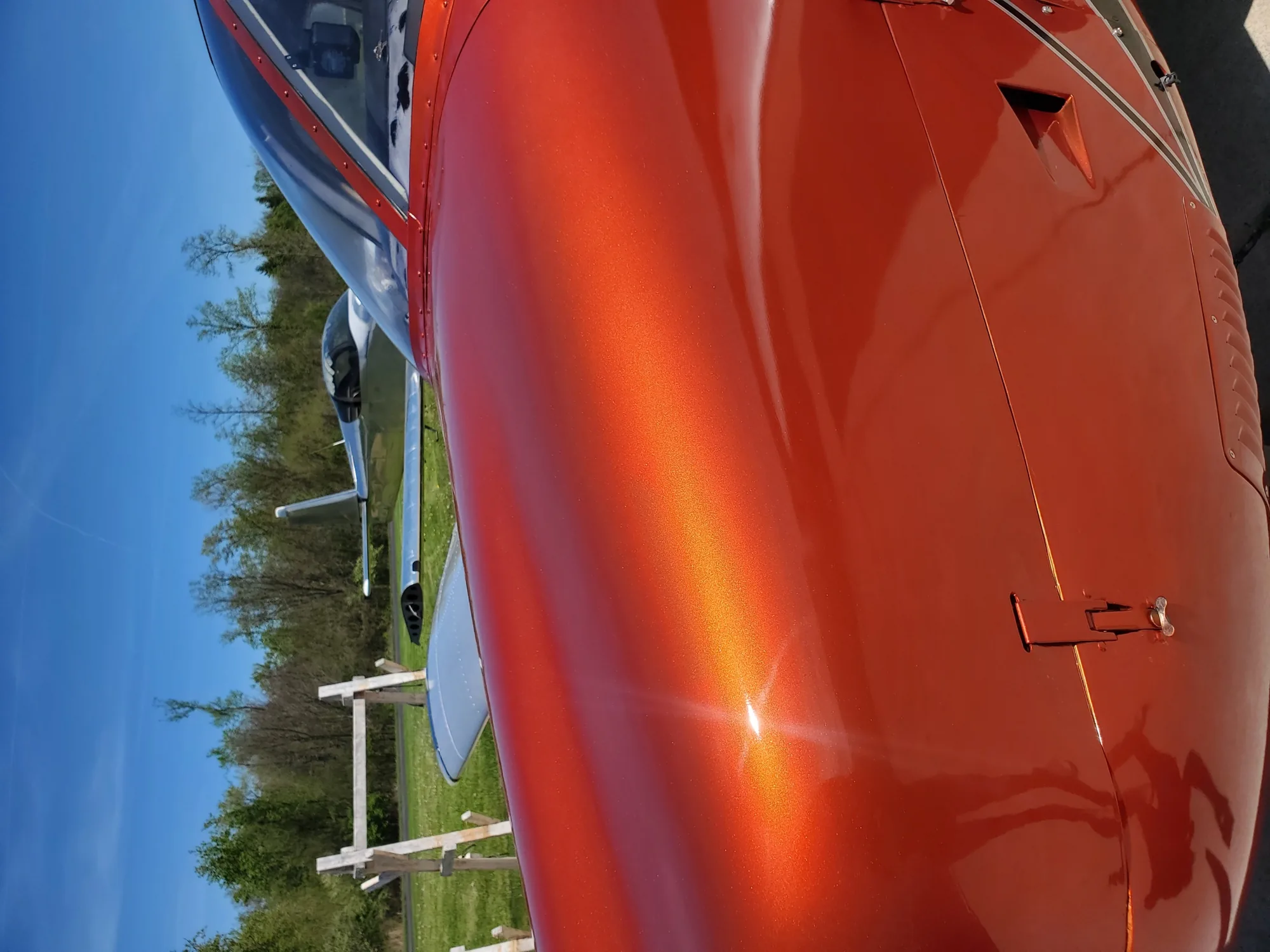 Metallic orange aircraft finish reflecting sunlight