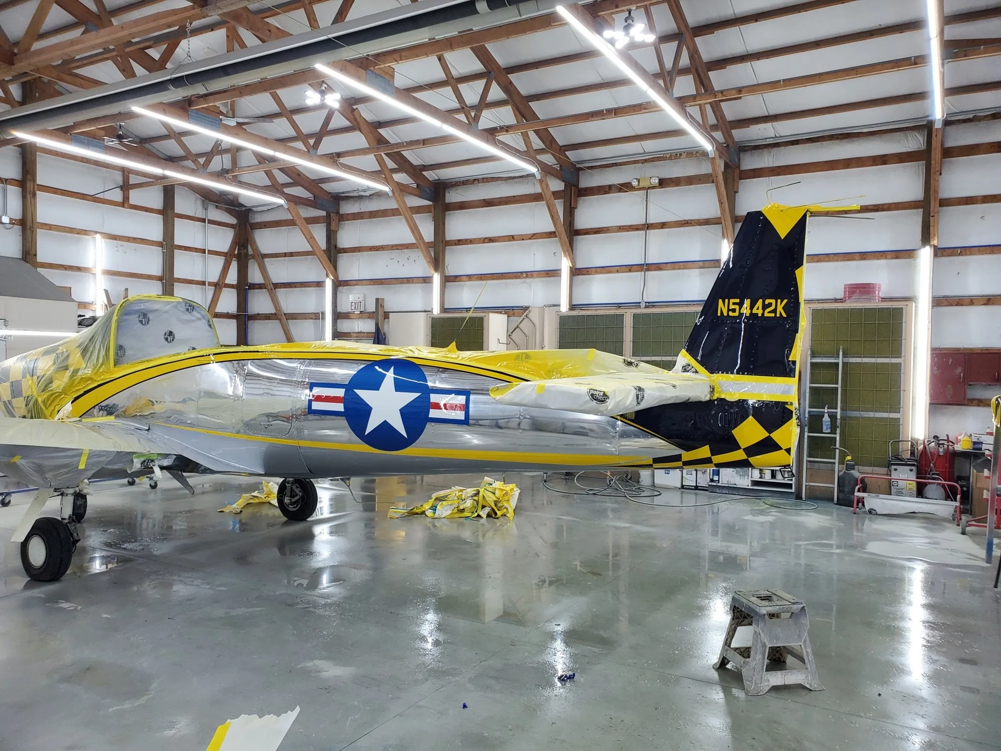 Yellow, black and polished aircraft being unmasked in the Hangar 74 shop